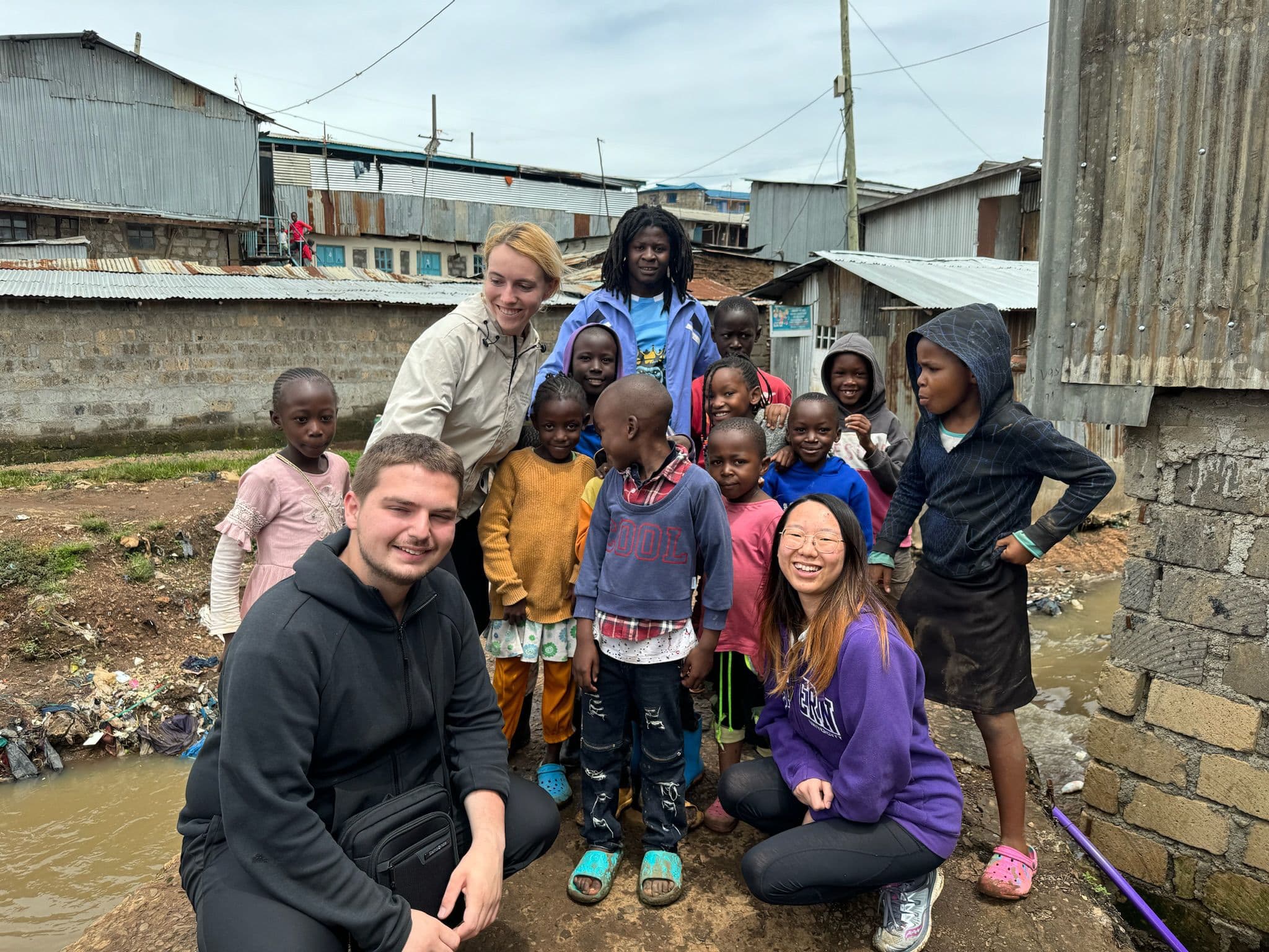 Xatoms team members with children beside a polluted waterway